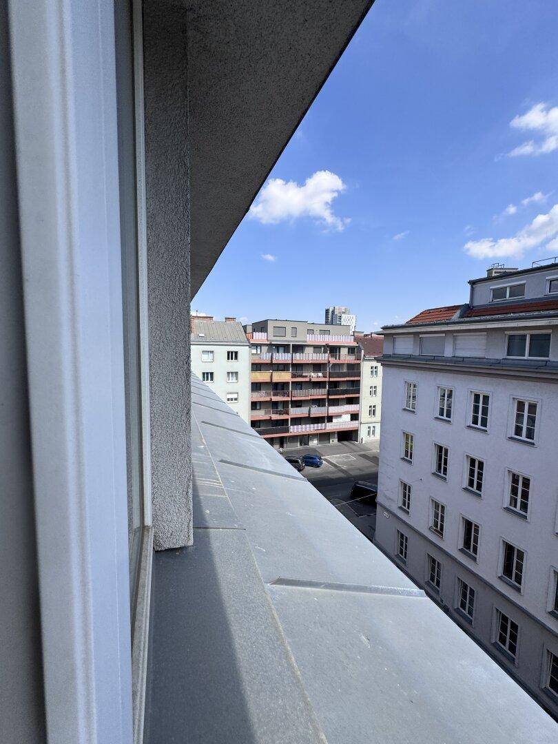 Blick aus dem Fenster auf die umliegenden Gebäude und die städtische Umgebung unter blauem Himmel.