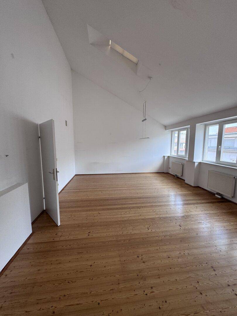 Geräumiger Raum mit warmem Holzboden, Dachfenstern und viel Tageslicht, perfekt für individuelle Gestaltung.
