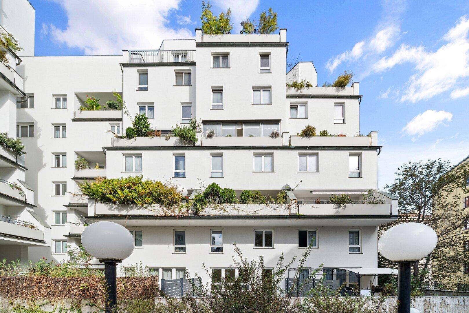 Modernes Wohngebäude mit mehreren Balkonen und begrünten Terrassen.