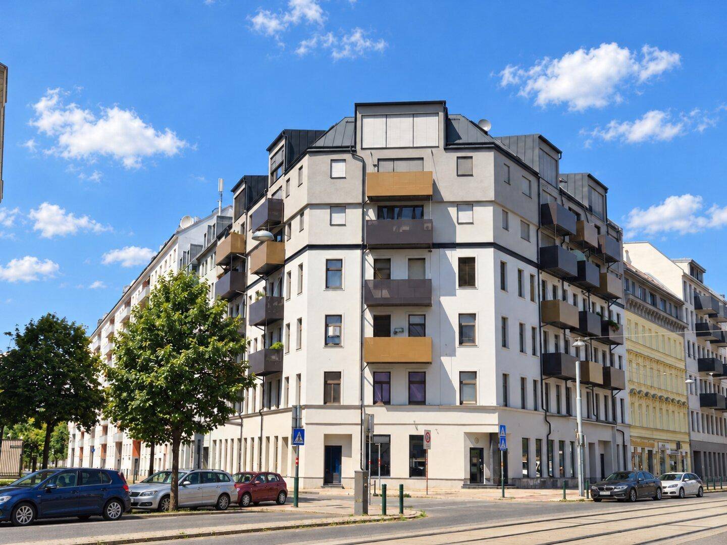 Modernes Wohngebäude mit mehreren Balkonen und einer markanten Fassade in städtischer Umgebung.