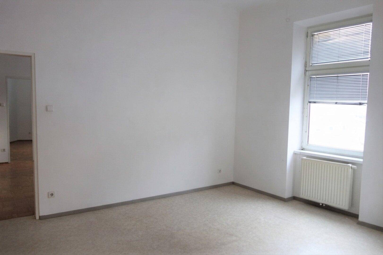 Helles Zimmer mit hellem Bodenbelag und einem Fenster, das viel natürliches Licht hereinlässt.