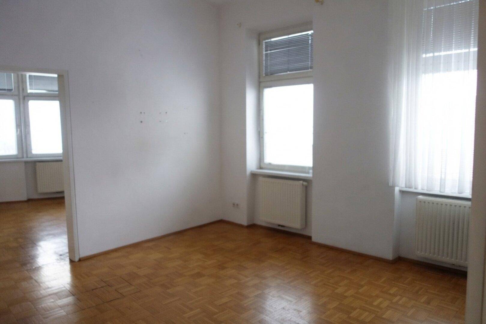 Geräumiges Zimmer mit Parkettboden und großen Fenstern, ideal für individuelle Einrichtungsideen.