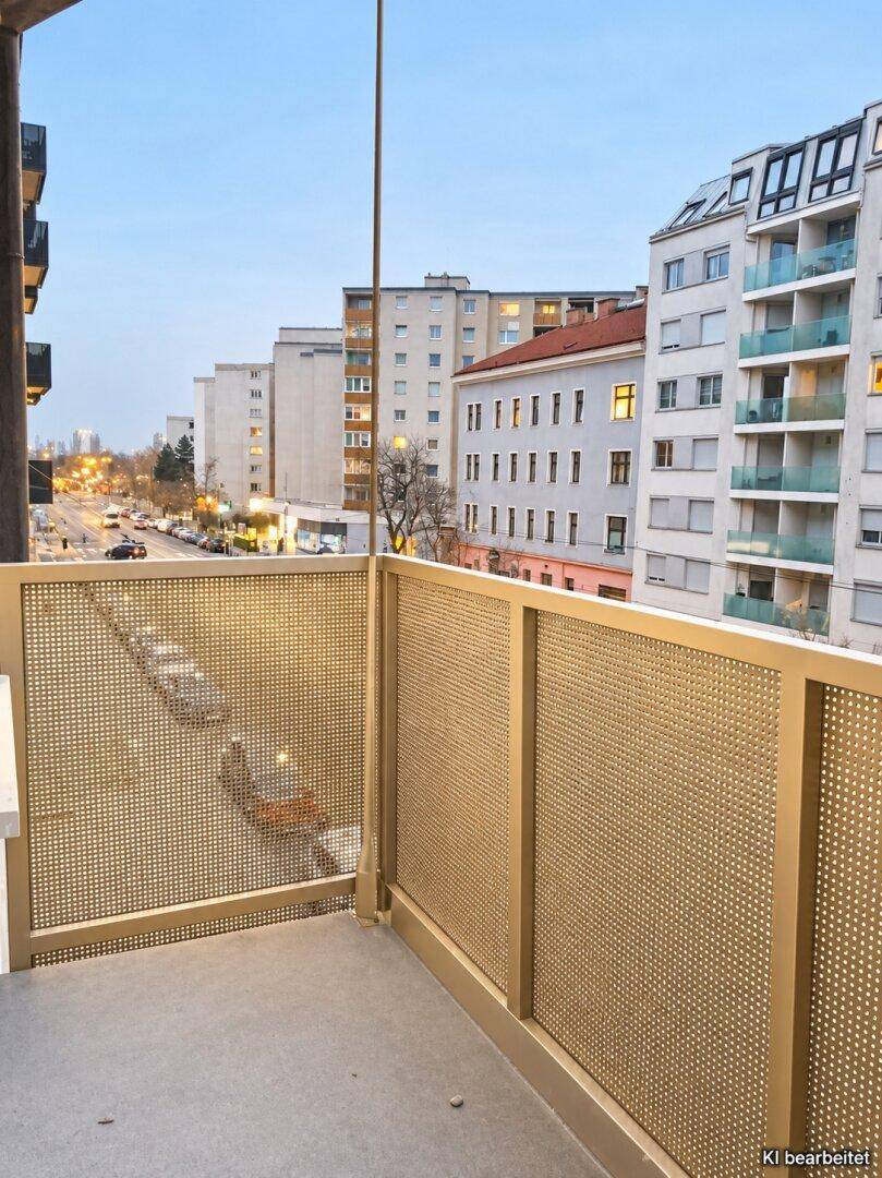 Balkon mit perforierter Brüstung und Blick auf die belebte Stadtstraße bei Dämmerung.