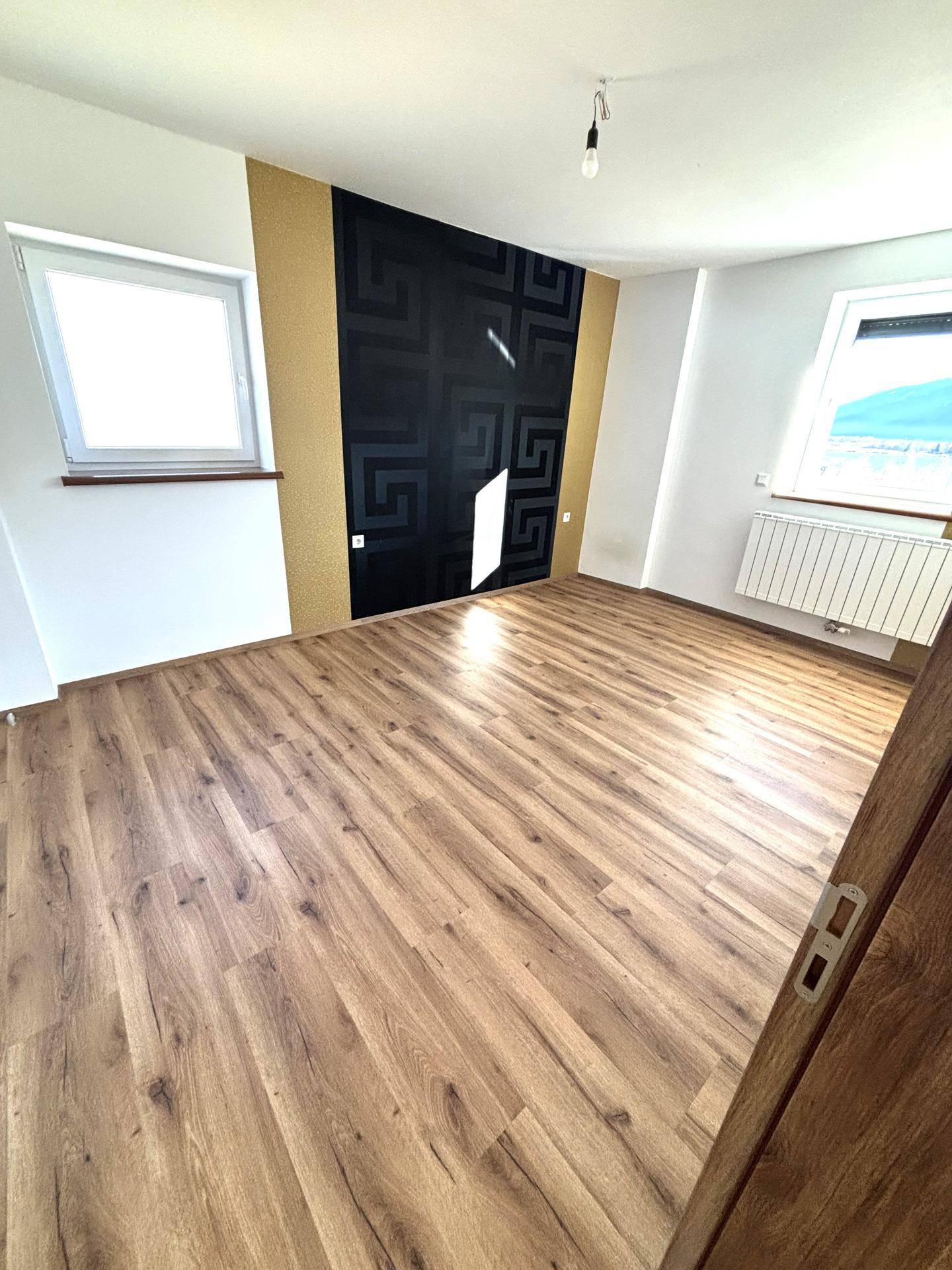 Schlafzimmer mit Laminatboden, Heizkörper und einer stilvollen Akzentwand.