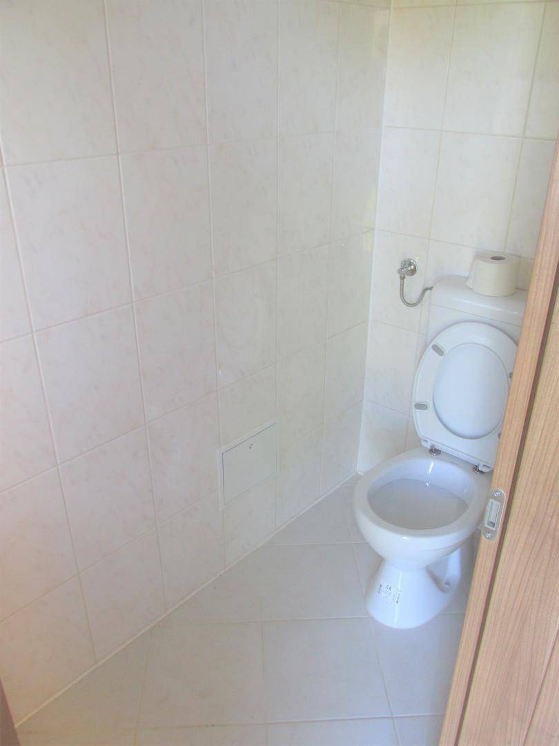 Einfaches WC mit weiß gefliesten Wänden und Boden, funktional und hell.