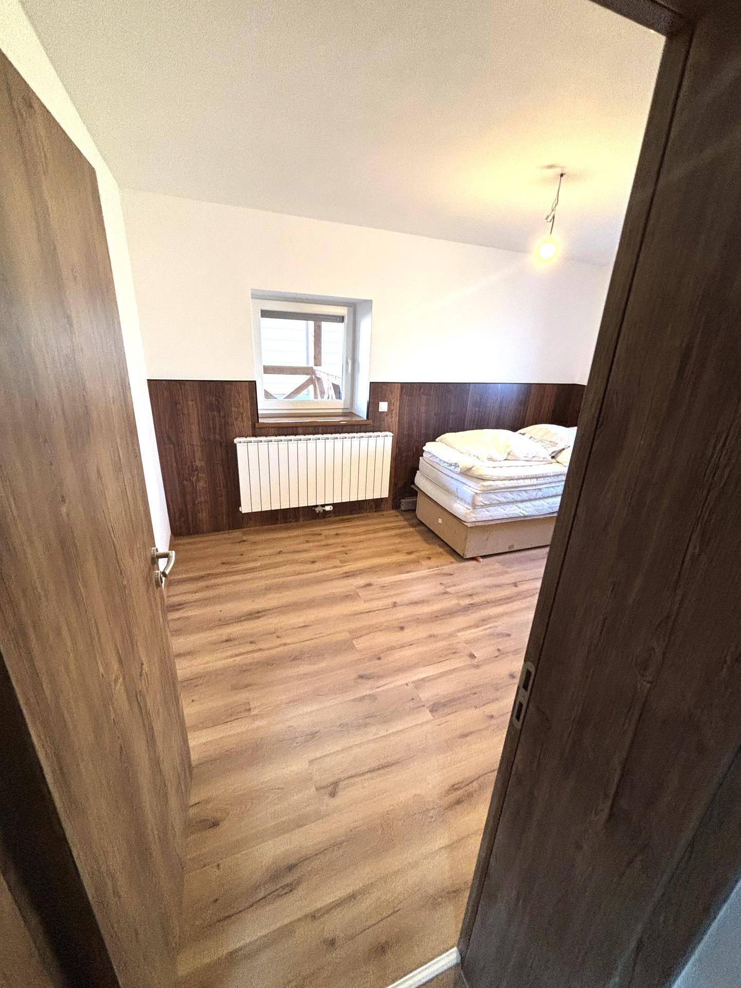 Gemütliches Schlafzimmer mit Laminatboden, Holzvertäfelung und einem bequemen Bett.