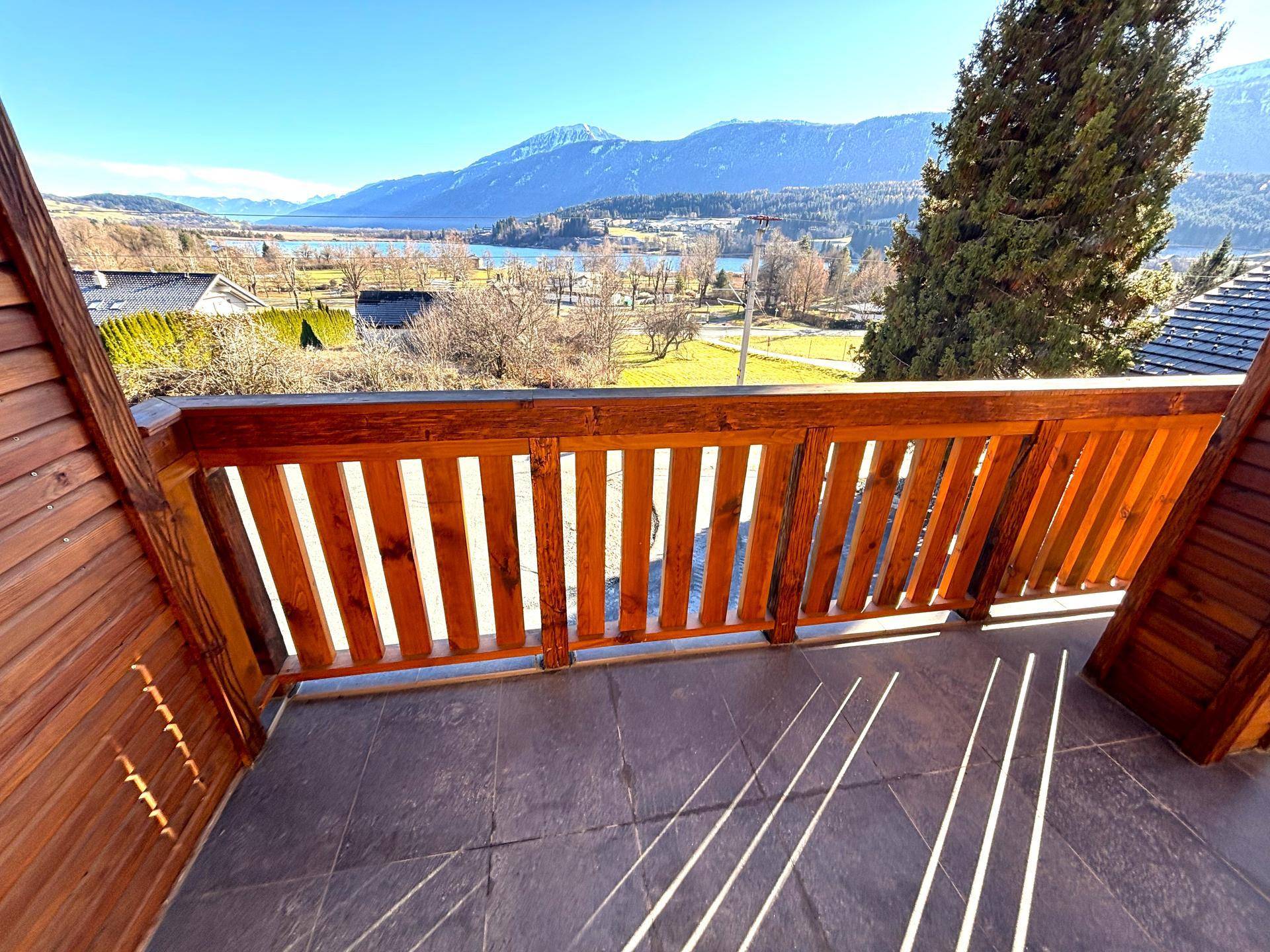 Großer Balkon mit Holzbalken und Fliesenboden, bietet einen weiten See- und Bergblick.