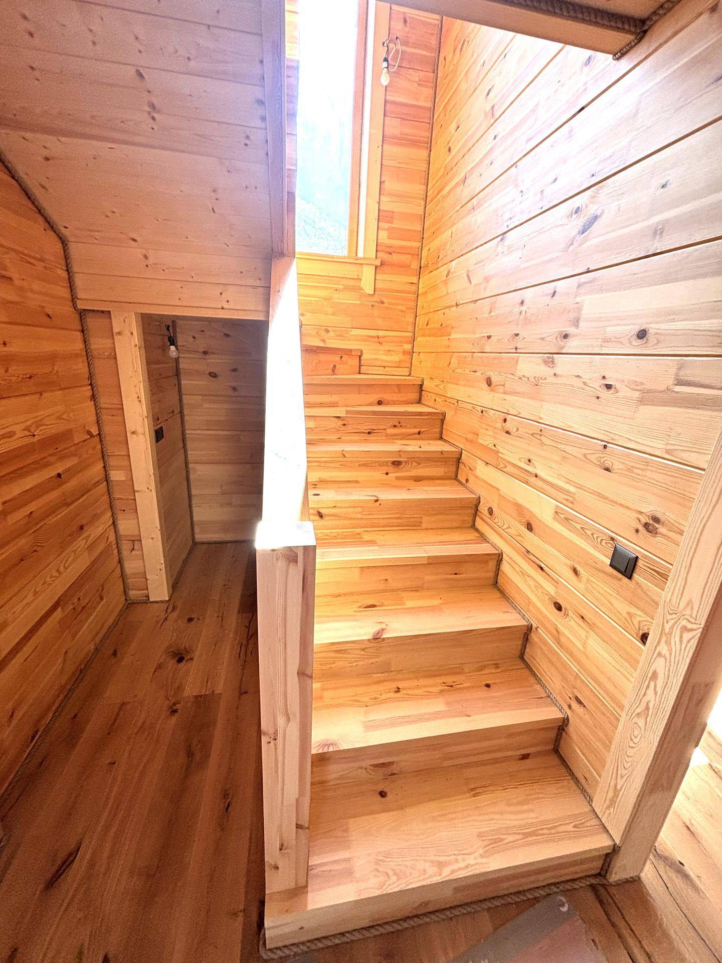 Holztreppe führt in die obere Etage, umgeben von heller Holzvertäfelung.