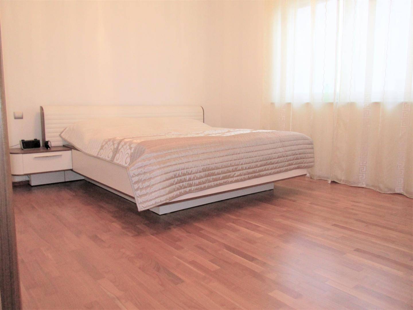 Helles Schlafzimmer mit großem Doppelbett und Holzboden, ideal für erholsame Nächte.