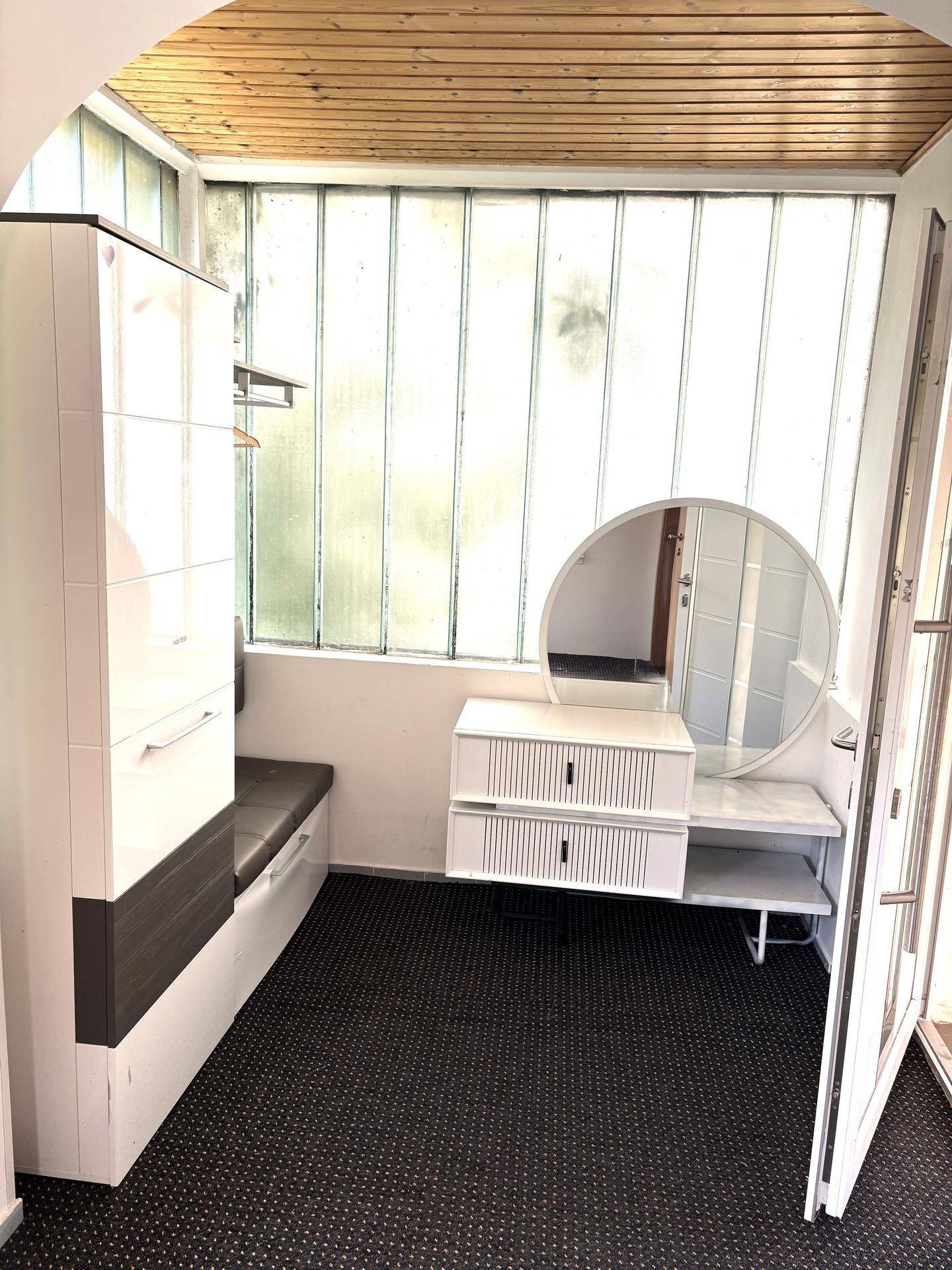 Heller Eingangsbereich mit Garderobe, Spiegel und Glasbausteinwand.