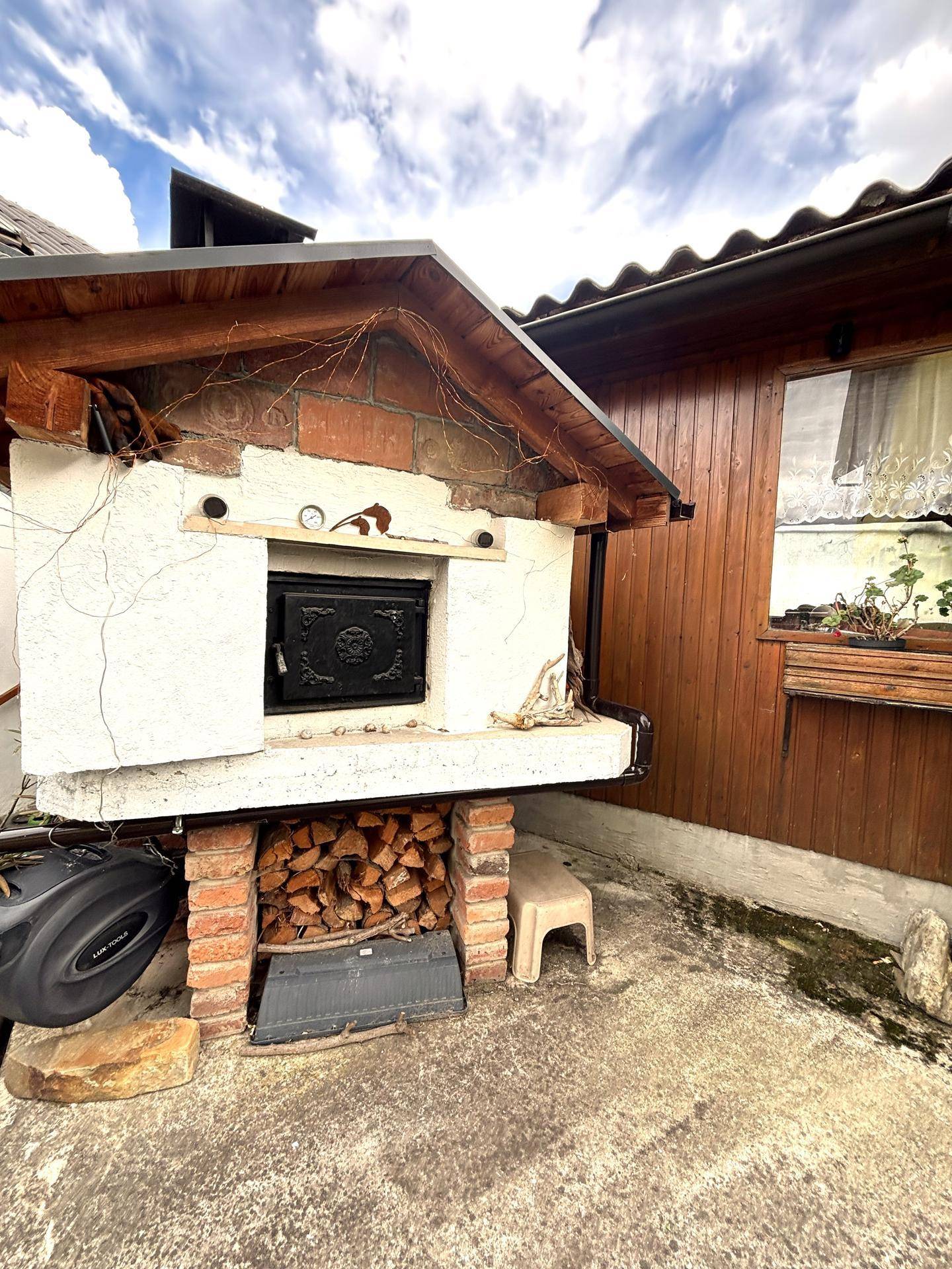 Außenofen mit Holzstapel und rustikaler Gestaltung, perfekt für Outdoor-Kocherlebnisse.