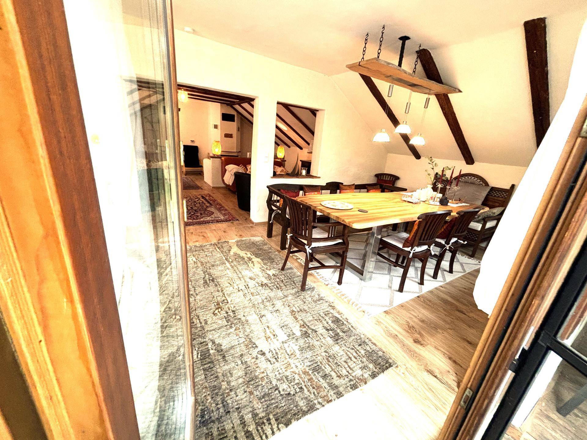 Geräumiger Essbereich mit großem Holztisch, Stühlen und Zugang zu einem Balkon.