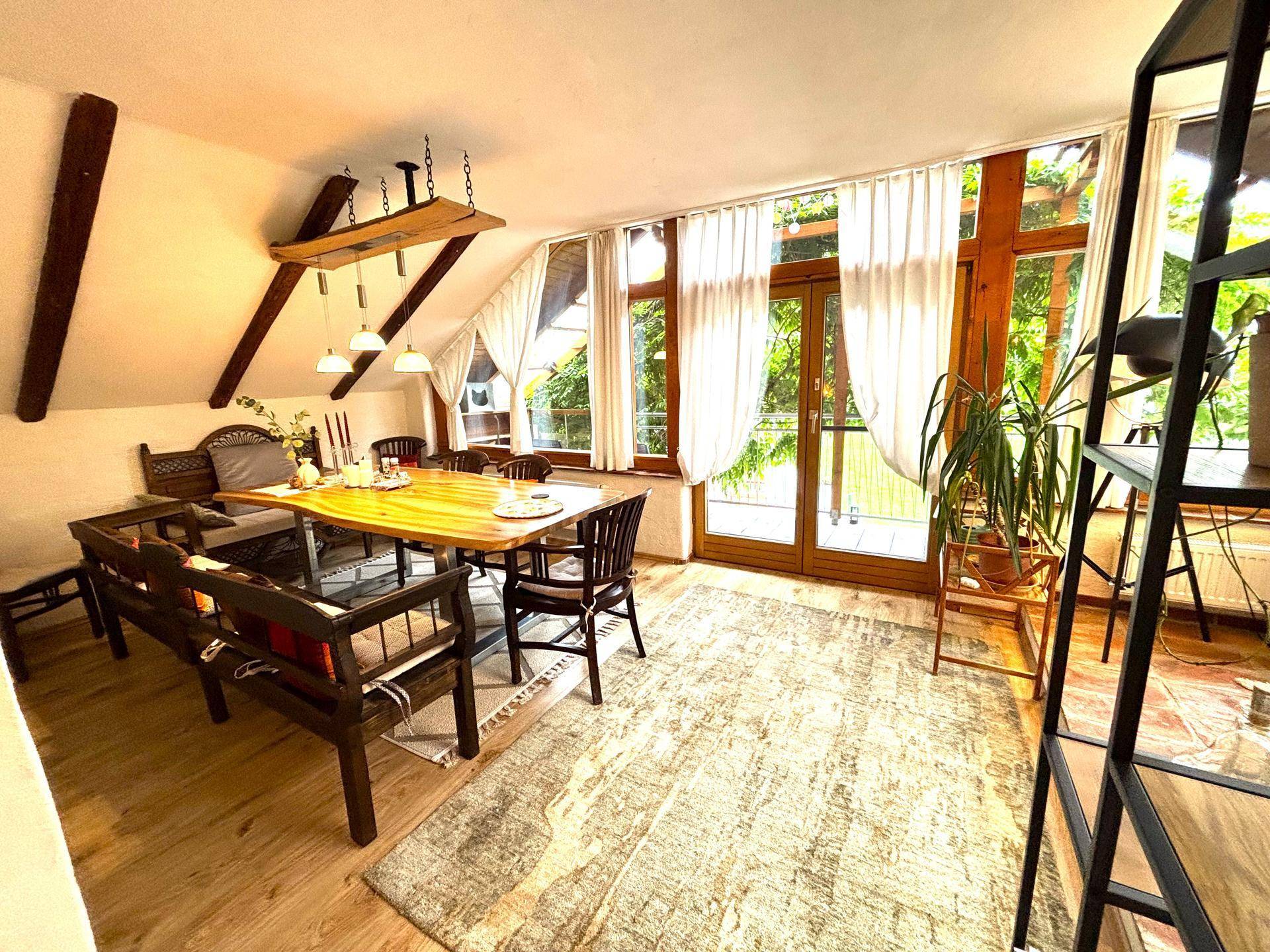 Geräumiger Essbereich mit großem Holztisch, Stühlen und Zugang zu einem Balkon.