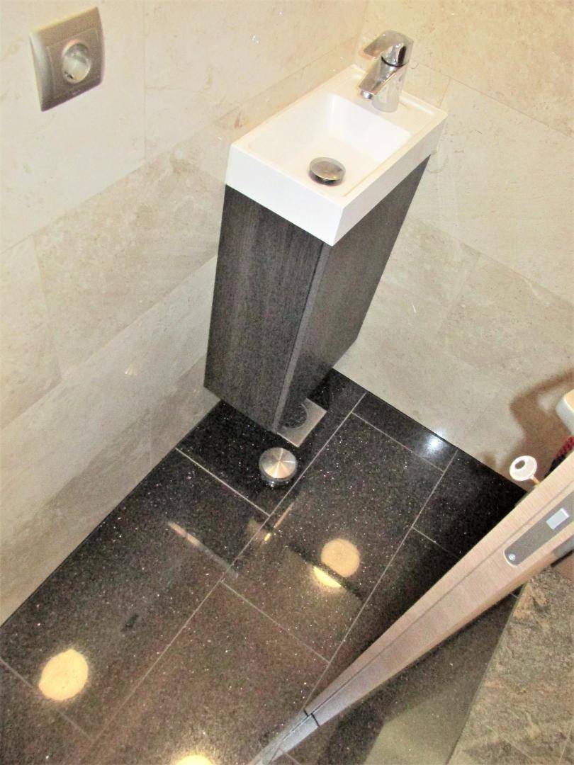 Kleines Waschbecken im Gäste-WC mit dunklem Fliesenboden und modernem Design.