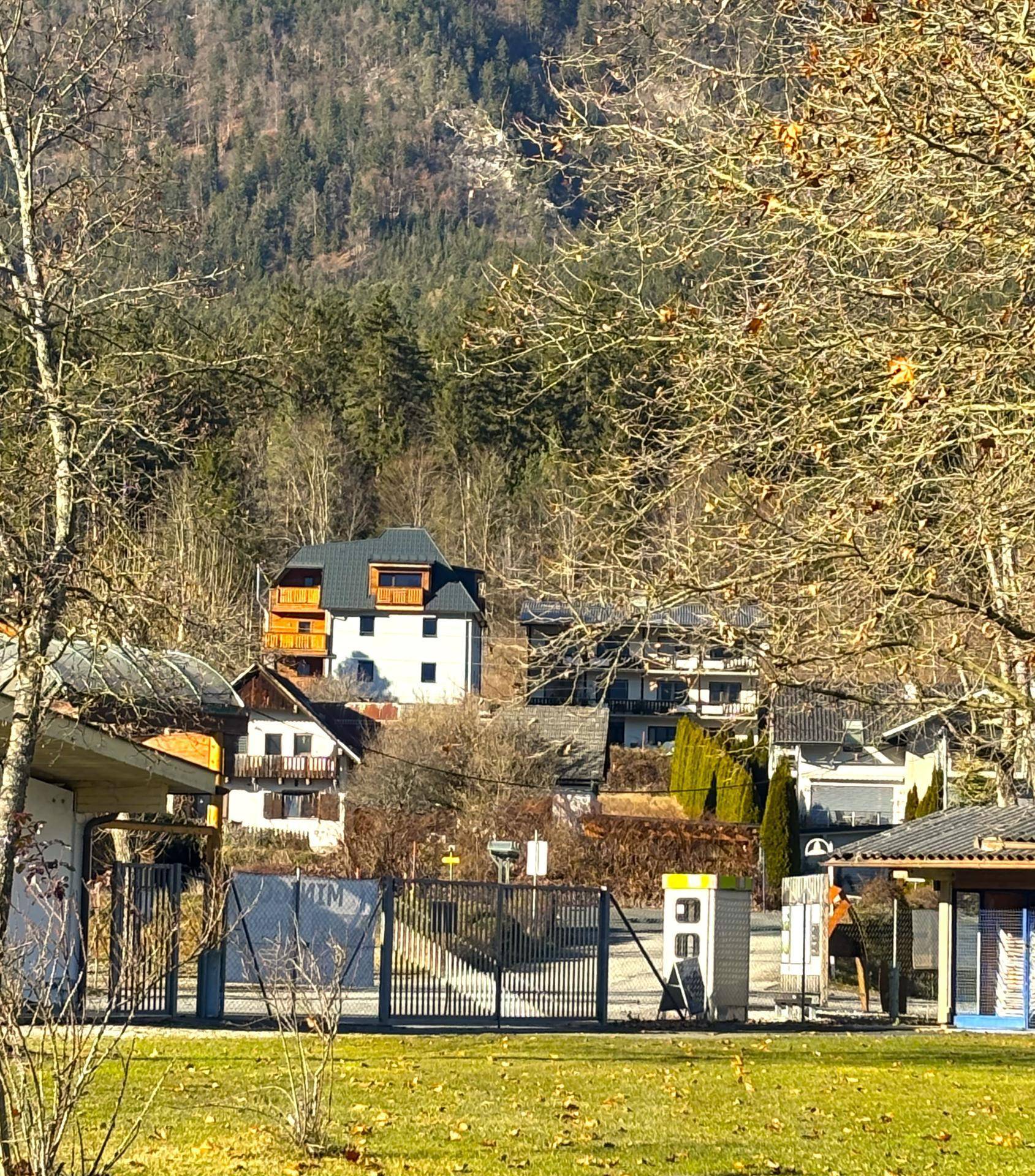 Malerischer Blick auf Häuser in einer ländlichen Umgebung, umgeben von Bergen und Bäumen.