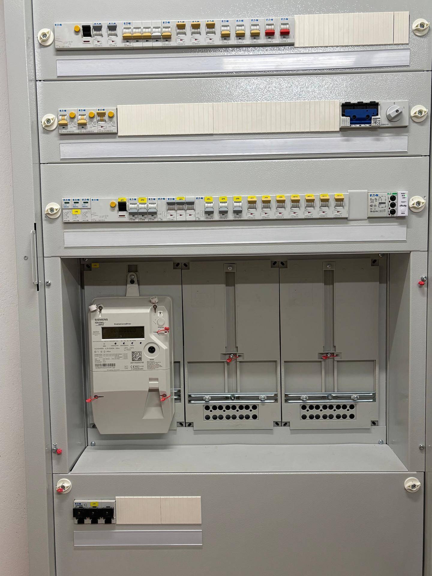 Moderner Sicherungskasten und Stromzähler in einem Technikraum, der die elektrische Versorgung regelt.