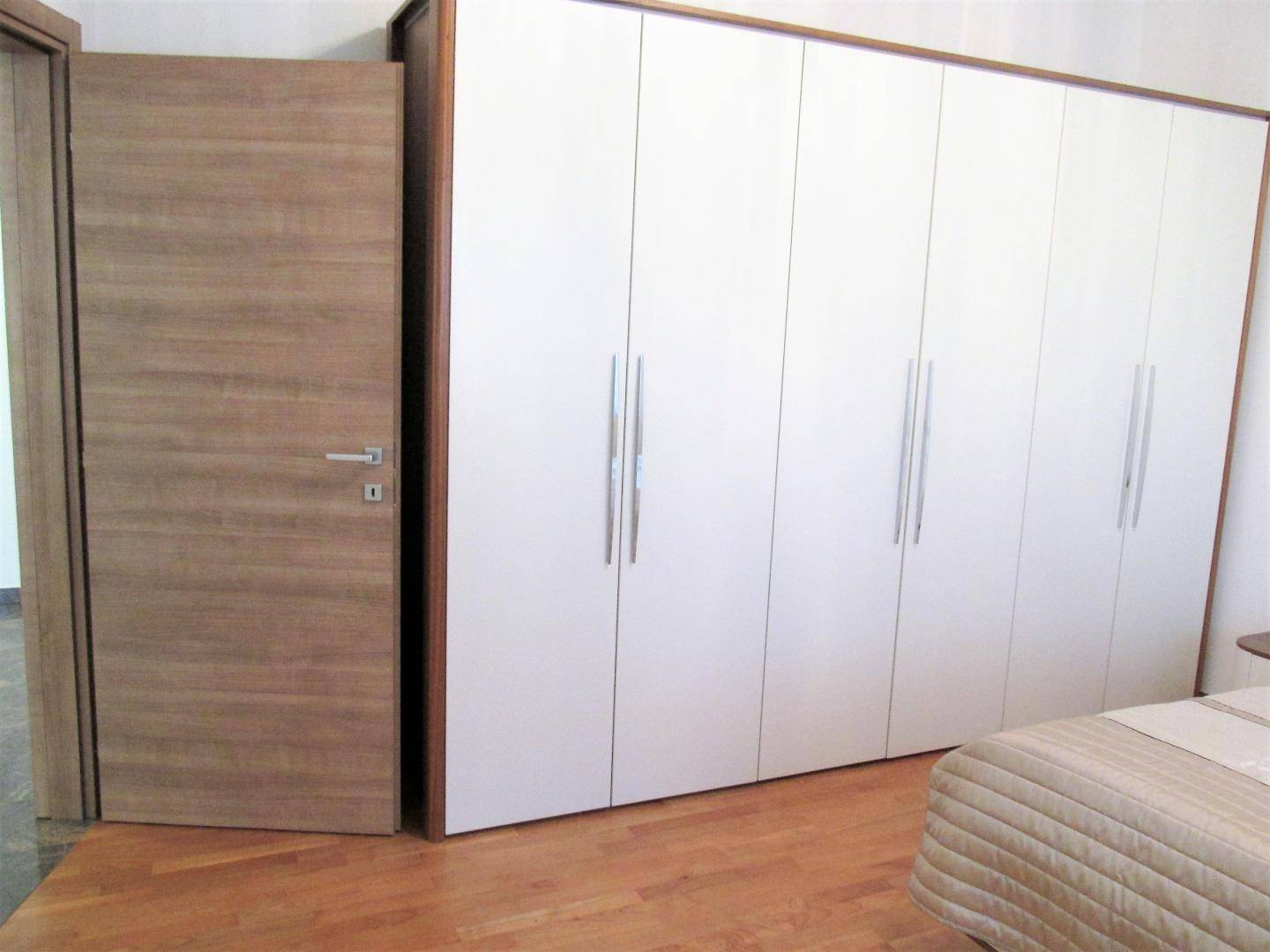 Schlafzimmer mit großem Einbauschrank und Holzboden, bietet viel Stauraum.