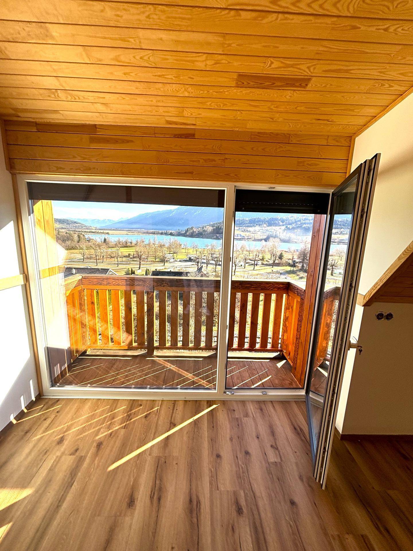 Große Fensterfront im Wohnbereich mit Blick auf den See und die umliegende Landschaft.