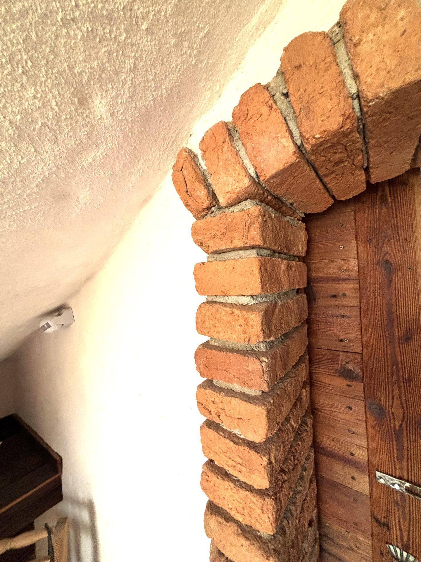 Detailaufnahme eines gemauerten Ziegelbogens mit rustikalem Charme im Innenbereich.