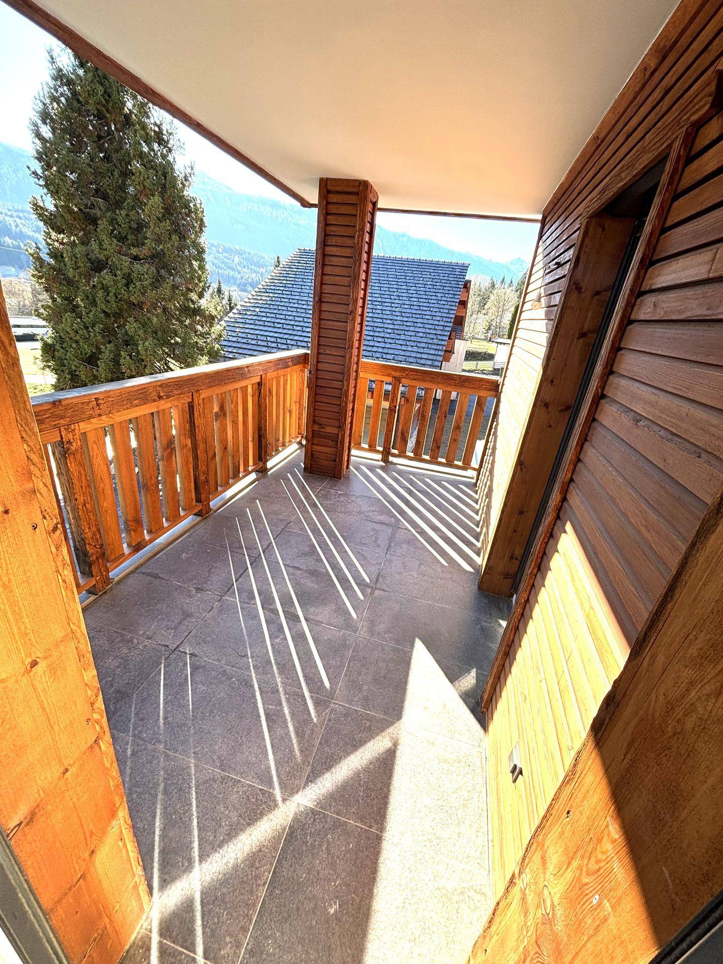 Sonniger Balkon mit Holzbalken und Fliesenboden, bietet einen malerischen Bergblick.