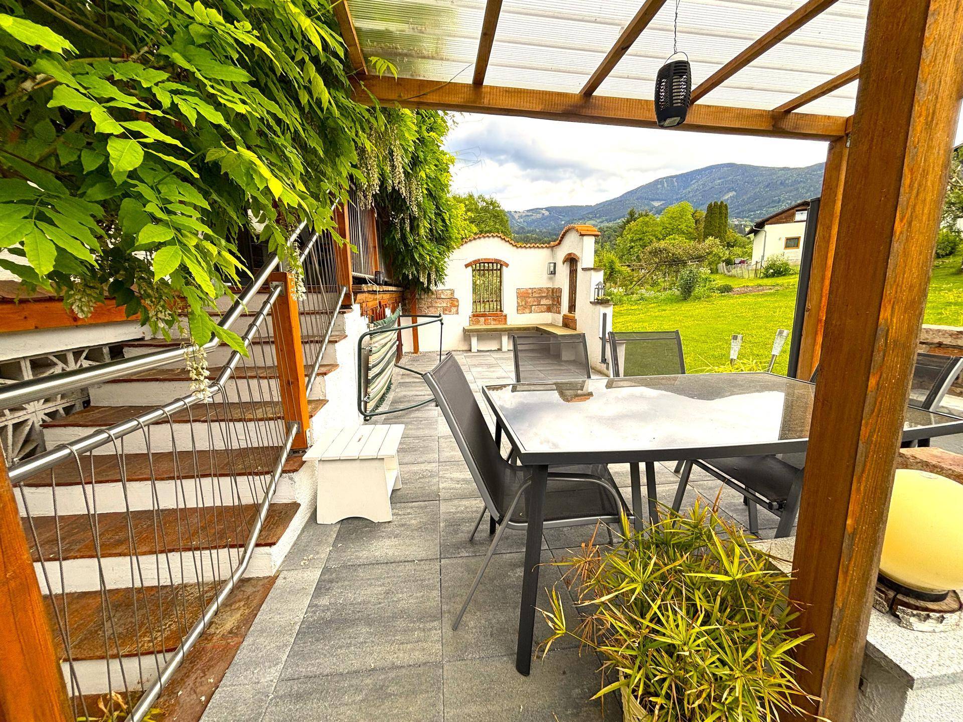 Große gepflasterte Terrasse mit Gartenmöbeln und weitem Blick auf die Landschaft.
