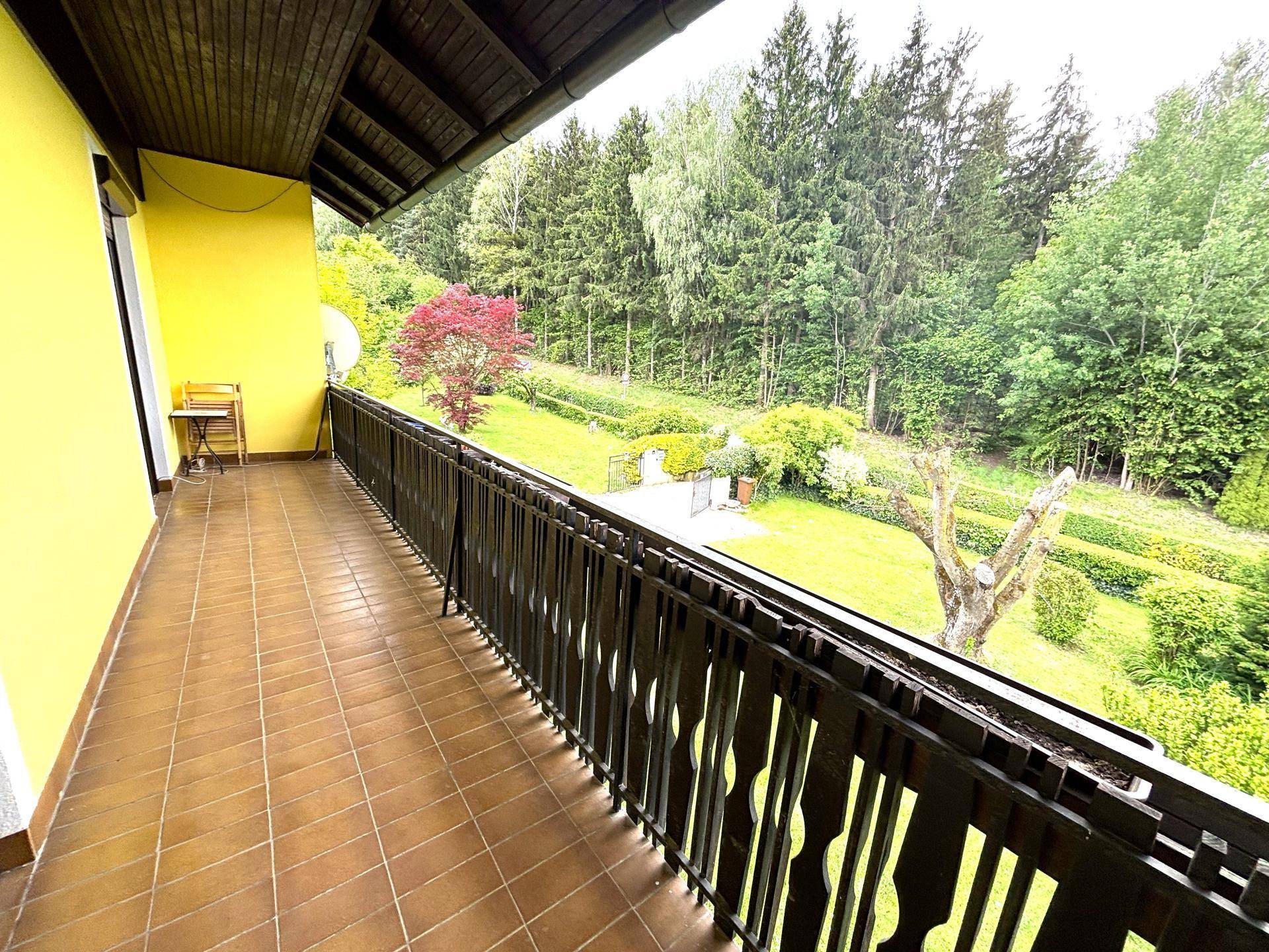 Langer Balkon mit Fliesenboden und Blick auf die umliegende grüne Landschaft.