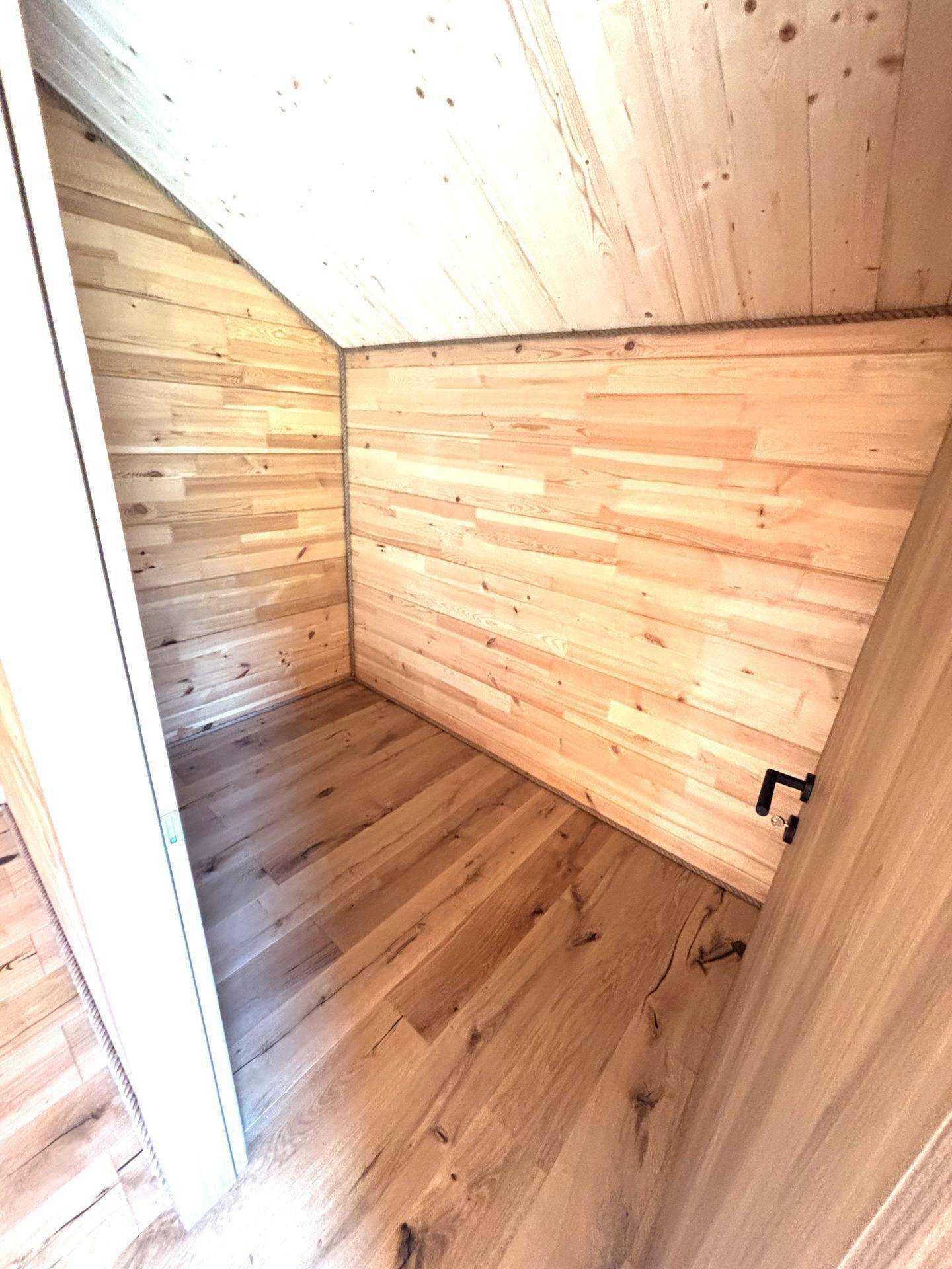 Praktischer Abstellraum im Dachgeschoss mit Holzboden und Holzvertäfelung unter der Dachschräge.