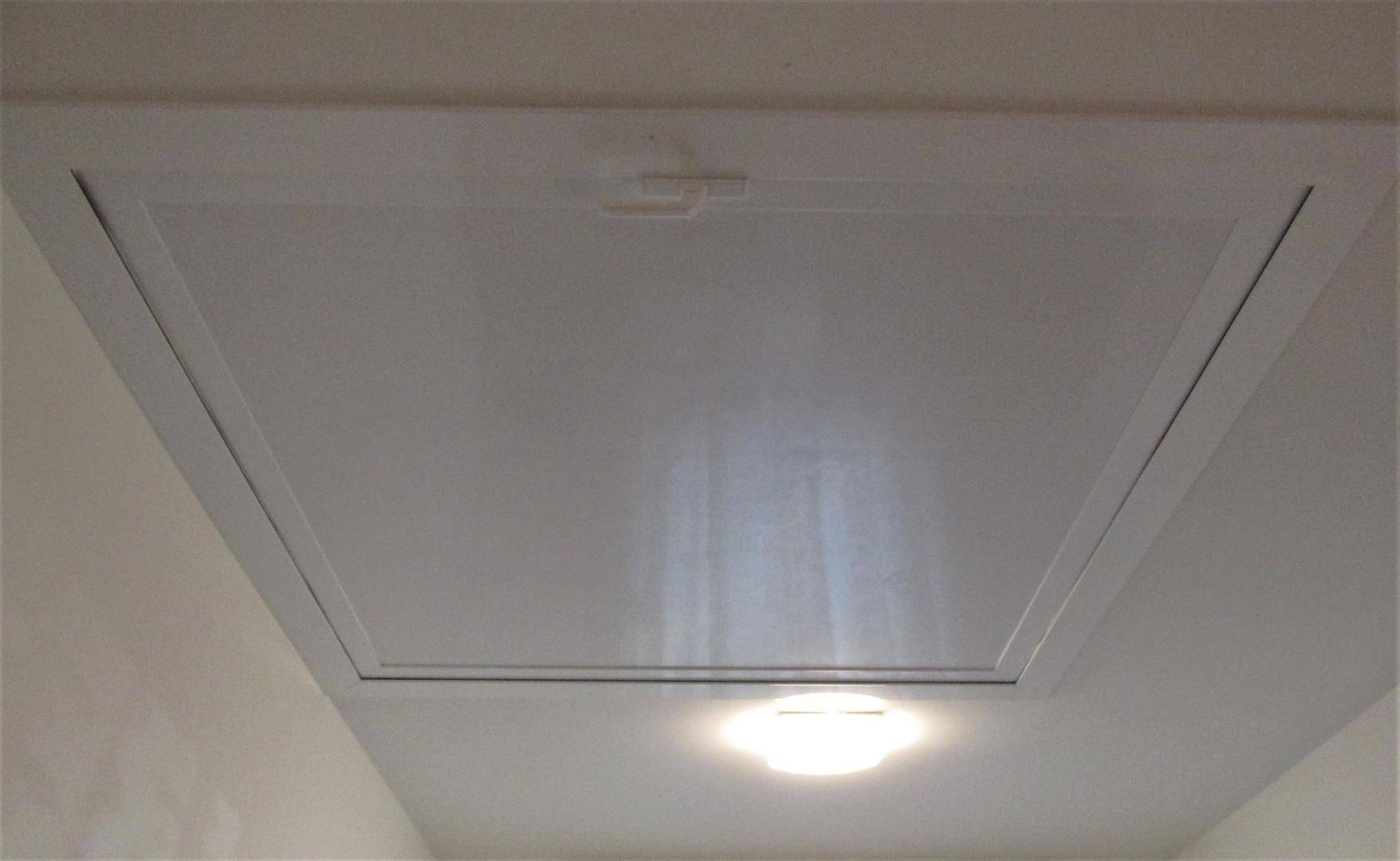Weiße Decke mit Zugangsklappe zum Dachboden und integrierter Beleuchtung in modernem Design.