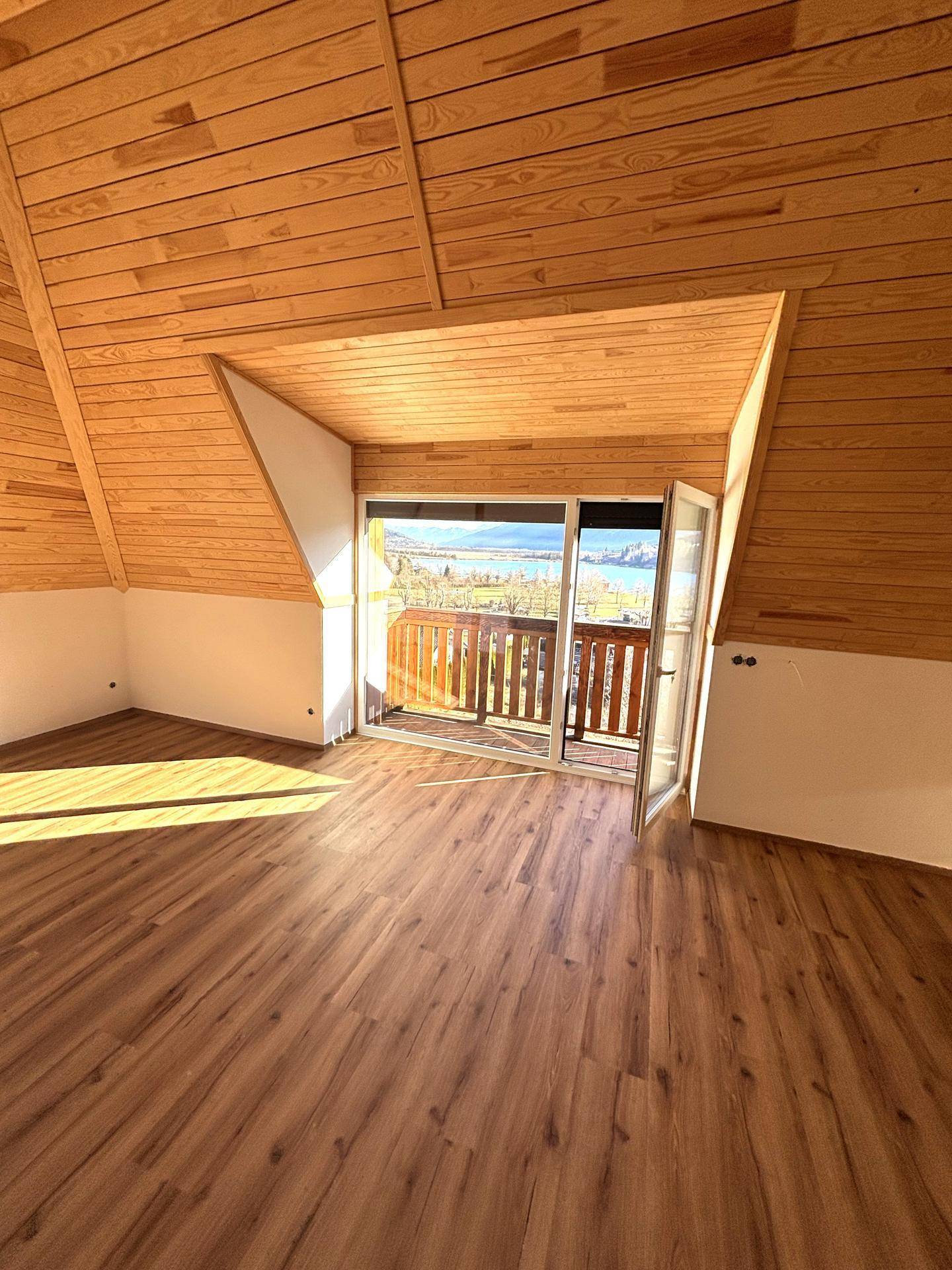 Geräumiger Wohnbereich mit Holzdachschrägen, Laminatboden und viel natürlichem Licht.