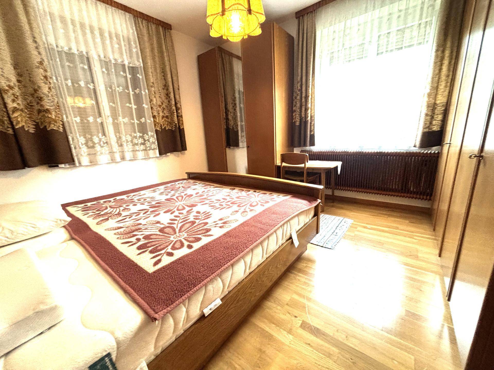 Schlafzimmer mit Holzboden, Doppelbett und Kleiderschrank.