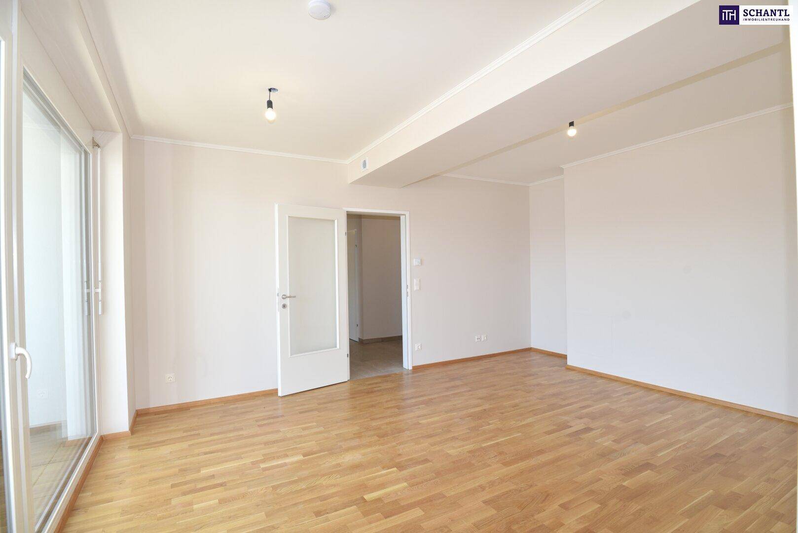Geräumiges Wohnzimmer mit hellem Parkettboden und großen Fenstern zum Balkon, lichtdurchflutet.