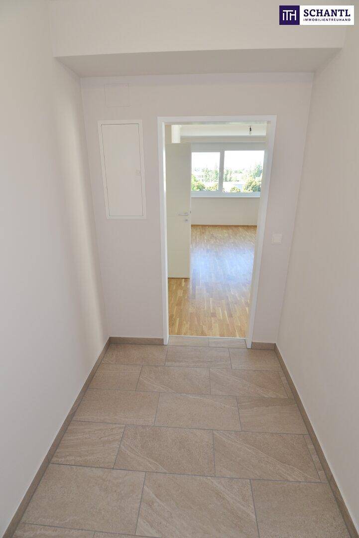 Heller Flur mit Fliesenboden und Übergang zu einem Zimmer mit Parkett, modern und gepflegt.