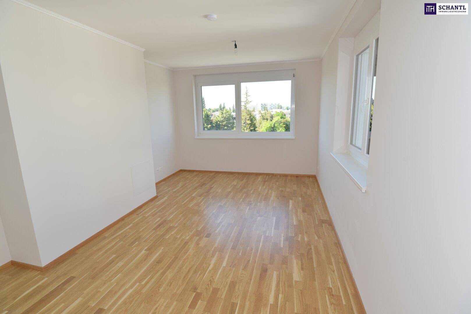 Geräumiges Zimmer mit hellem Parkettboden und zwei großen Fenstern, viel Tageslicht.