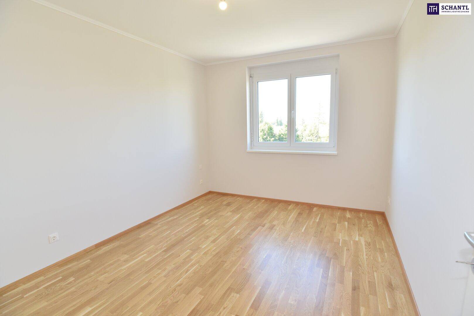 Helles Zimmer mit Parkettboden und einem großen Fenster, bietet viel natürliches Licht.