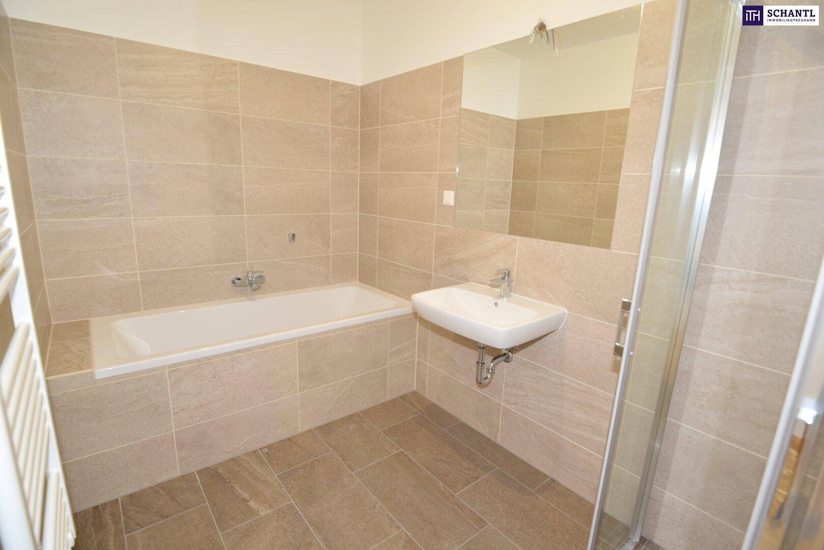 Modernes Badezimmer mit beigefarbenen Fliesen, Badewanne, Dusche und beheiztem Handtuchhalter.