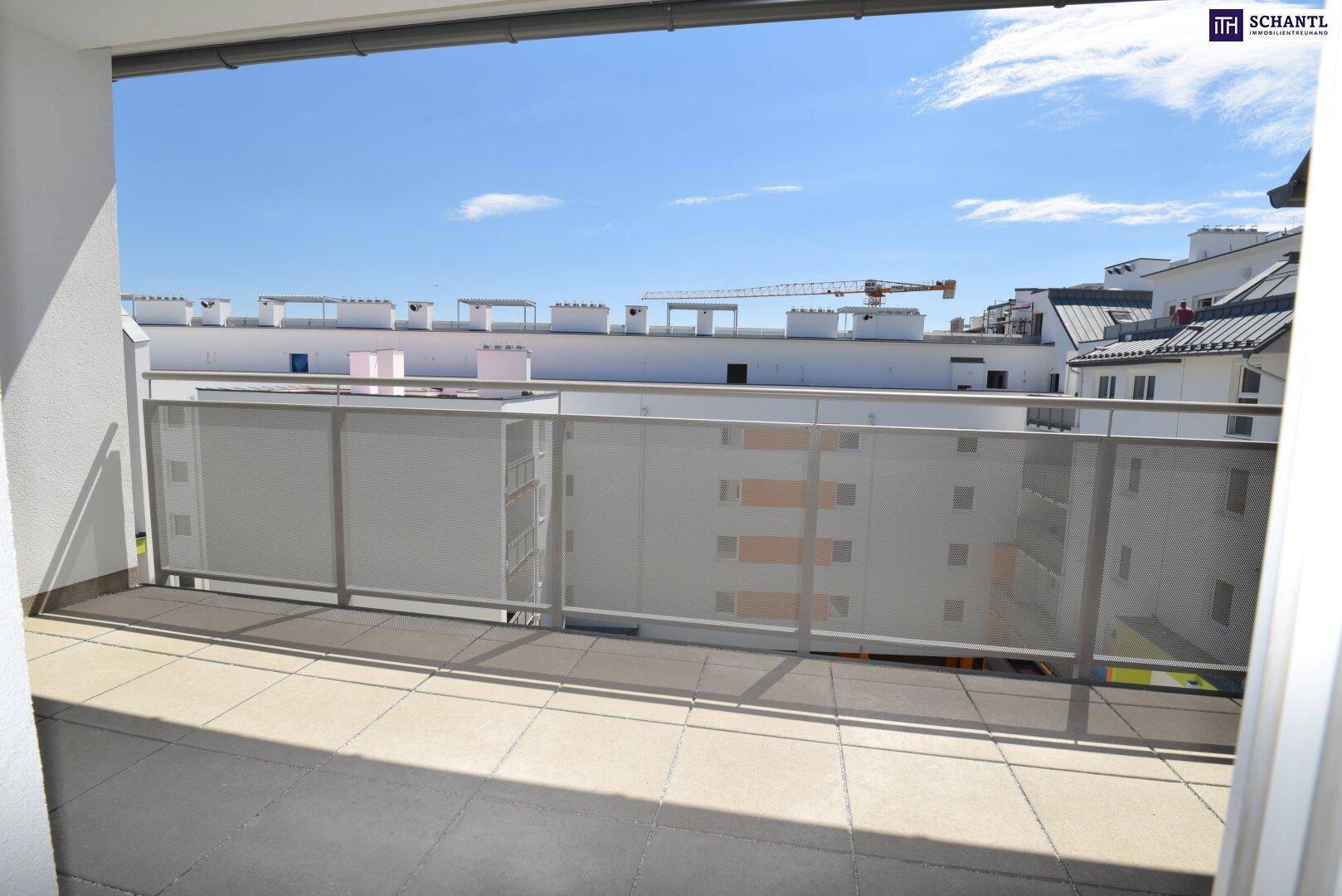 Heller Balkon mit Fliesenboden und weitem Blick über die umliegende Bebauung unter blauem Himmel.