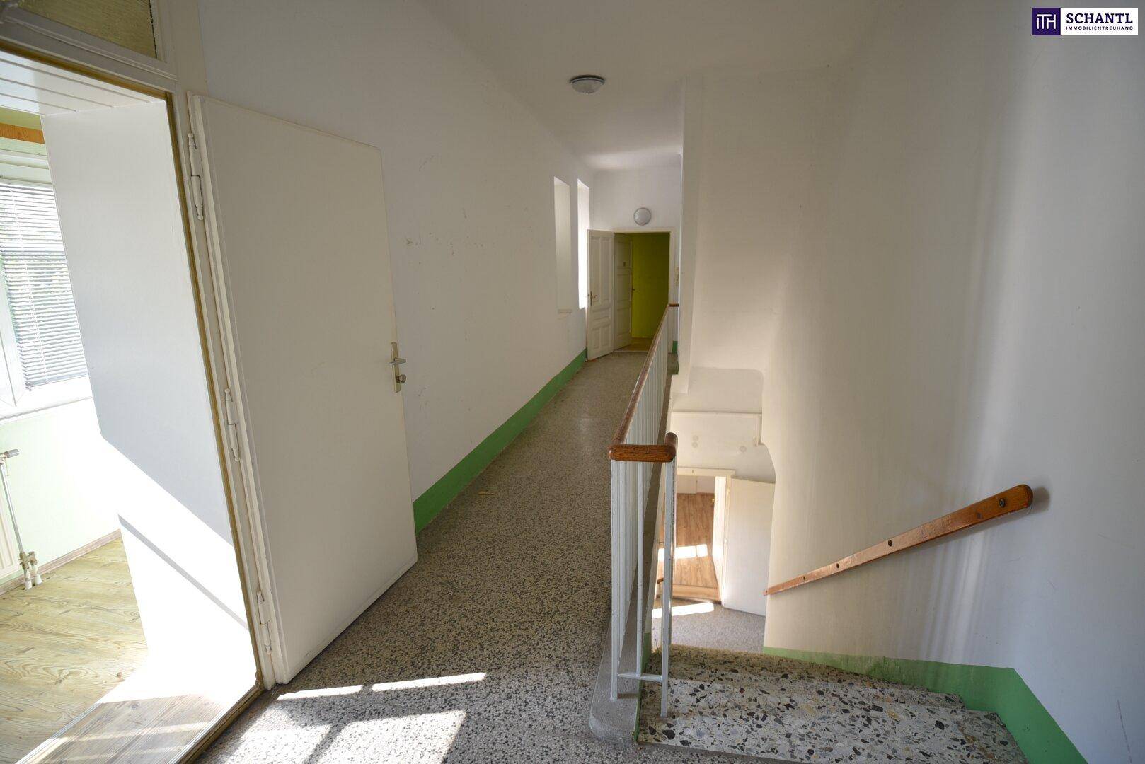 Heller Hausflur mit Terrazzoboden und Treppenaufgang, der zu weiteren Etagen führt.