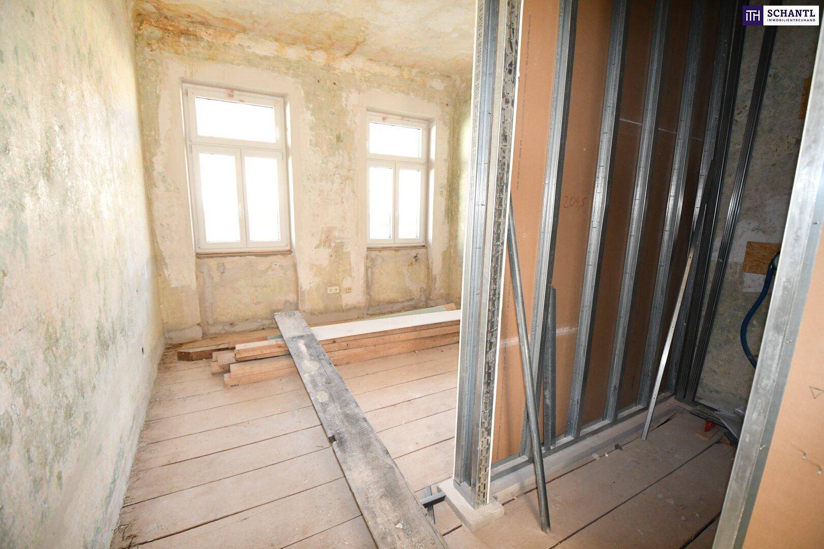 Renovierungsbedürftiger Raum mit freigelegten Wänden, Holzdielenboden und Bauholz.