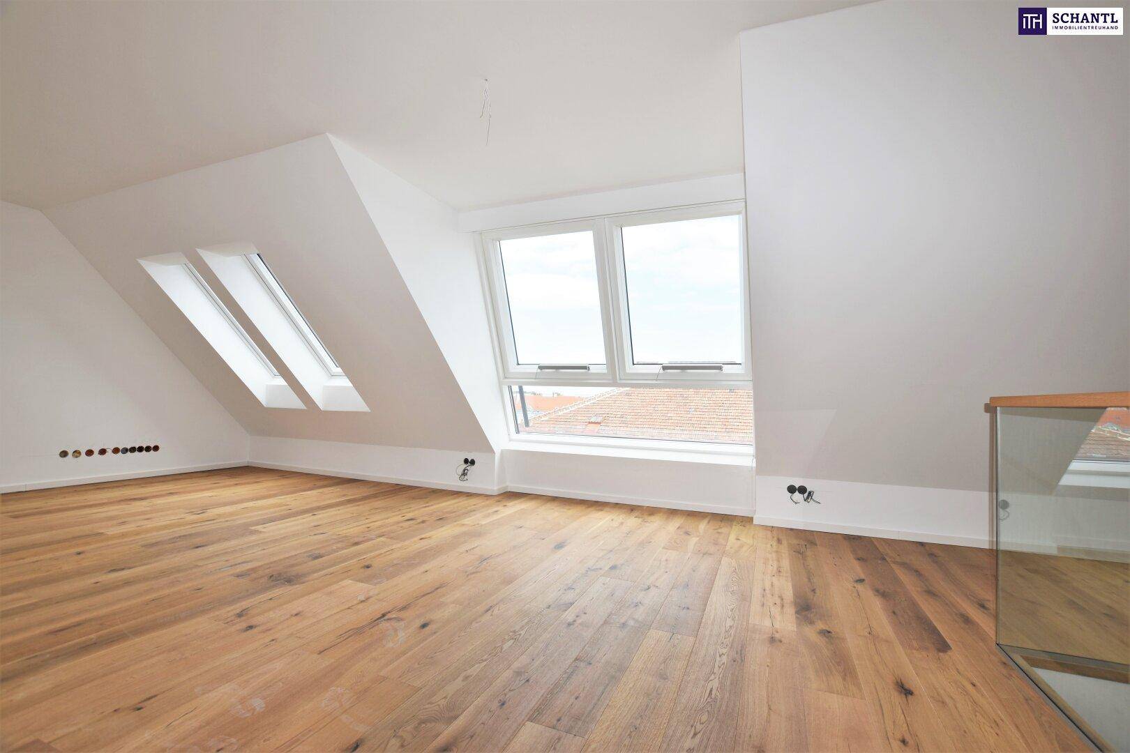 Lichtdurchfluteter Dachgeschossraum mit Holzboden, Dachschrägen und mehreren Fenstern.