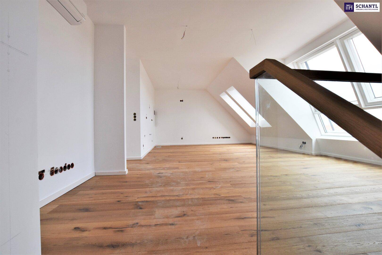 Geräumiger Dachgeschossraum mit Holzboden, Klimaanlage und großen Fenstern, noch im Ausbau.