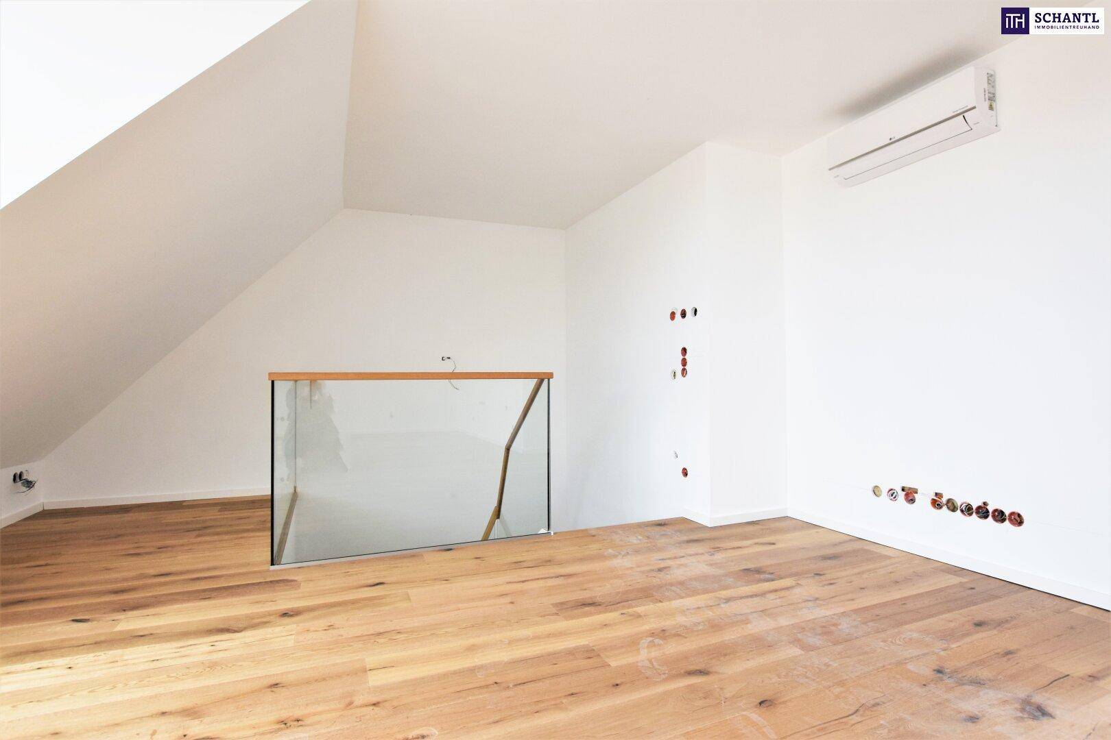 Dachgeschossraum mit Holzboden, Dachschräge, Klimaanlage und Glasgeländer.