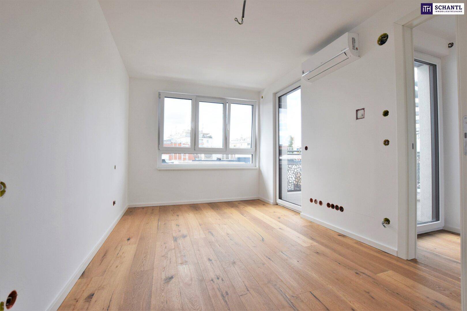 Heller Raum mit Holzboden, Klimaanlage und Zugang zu einem kleinen Balkon.