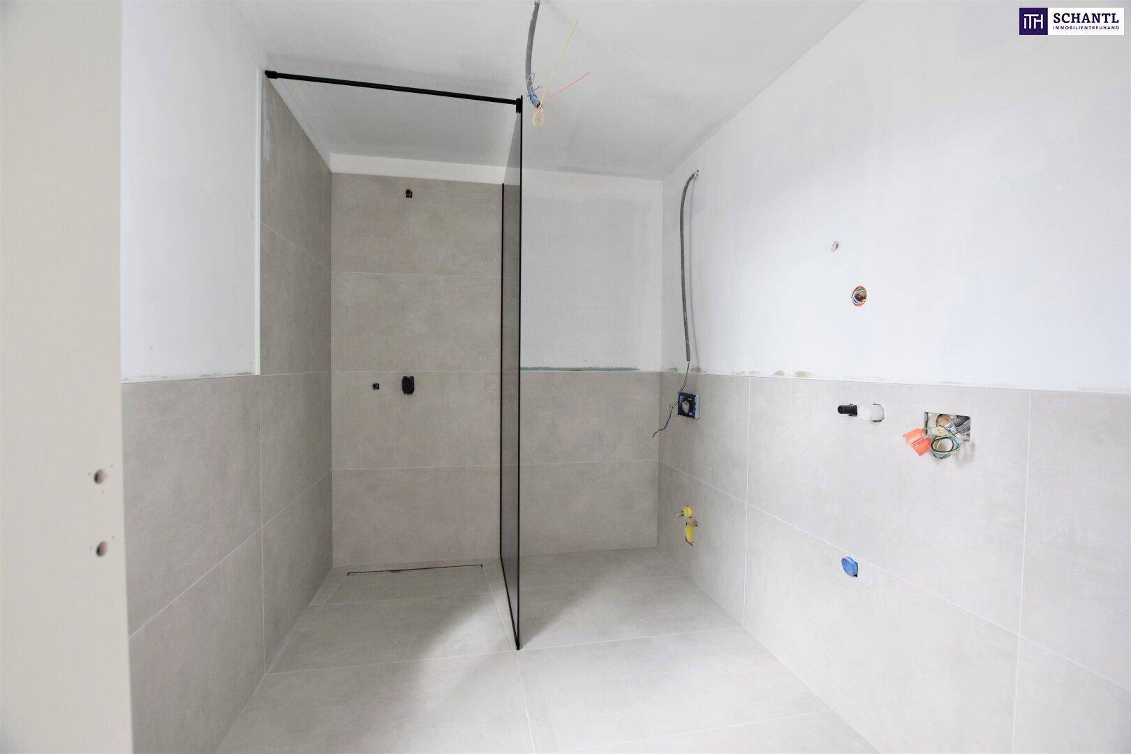 Modernes Badezimmer im Ausbau mit hellen Fliesen und Glasduschwand.