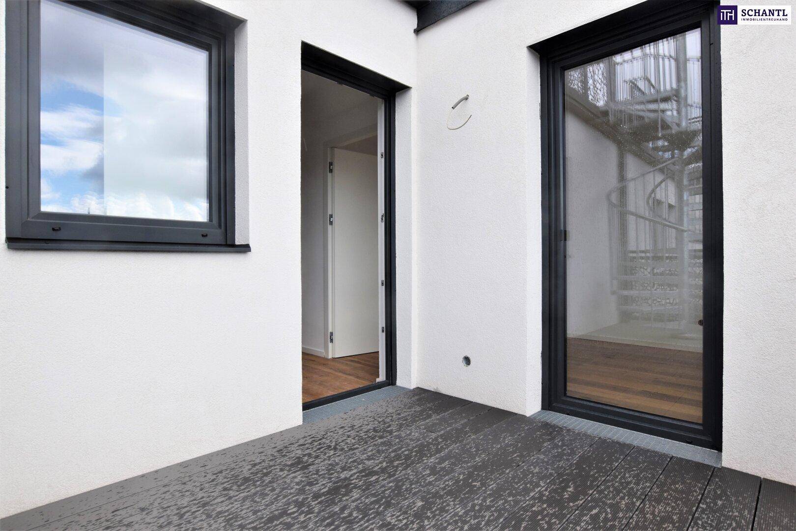 Kleiner Außenbereich mit dunklem Bodenbelag und Zugang zu einer Wendeltreppe.