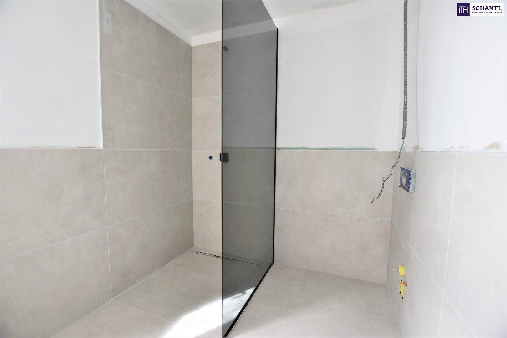 Modernes Badezimmer im Ausbau mit hellen Fliesen und Glasduschwand.