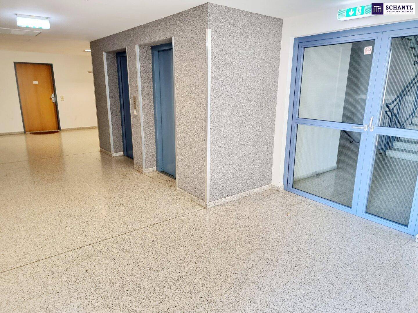 Heller Eingangsbereich mit zwei Aufzügen, gefliestem Boden und Zugang zum Treppenhaus.