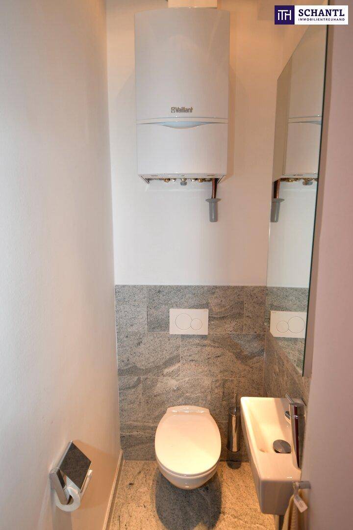 Kompaktes Gäste-WC mit wandhängendem WC, kleinem Waschbecken und modernem Steinfliesen-Design.