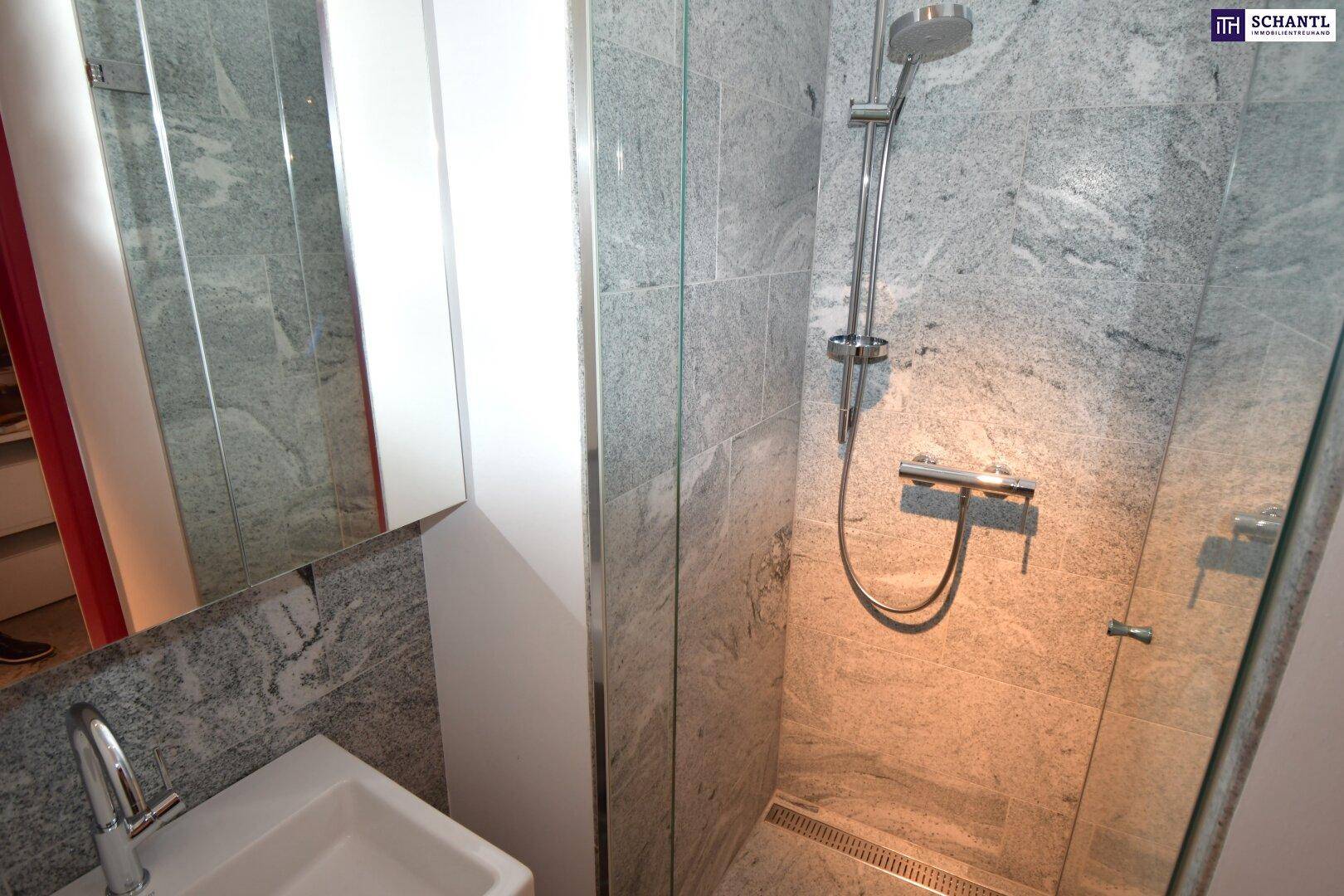 Modernes Badezimmer mit begehbarer Dusche, eleganten Steinfliesen und einem einzelnen Waschbecken.