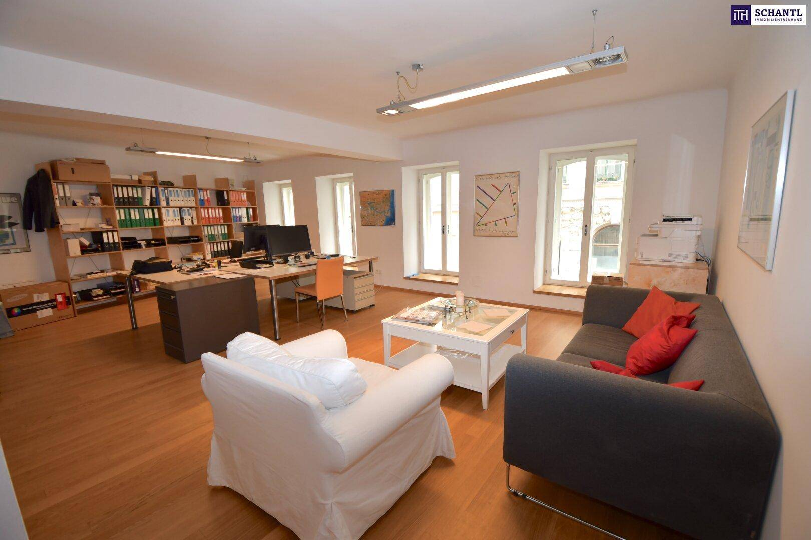 Komfortabler Lounge-Bereich im Büro mit Sofa, Sessel und Blick auf die Arbeitsplätze.