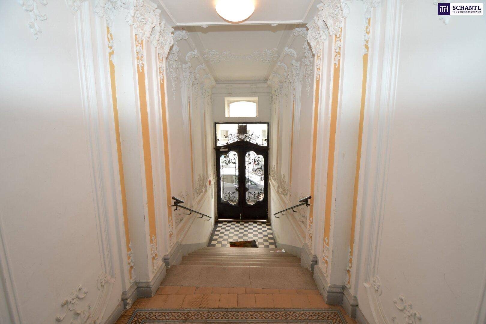 Repräsentatives Treppenhaus mit Stuckdecken, kunstvollen Verzierungen und einer eleganten Eingangstür.